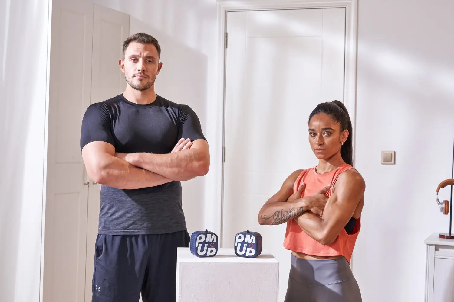 Un sportif et une sportive à côté de deux PUMP Pro bleus, musculation poulie à la maison